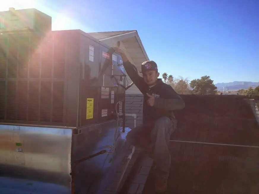 HVAC technician performing Boiler Repair on a rooftop unit in Selma